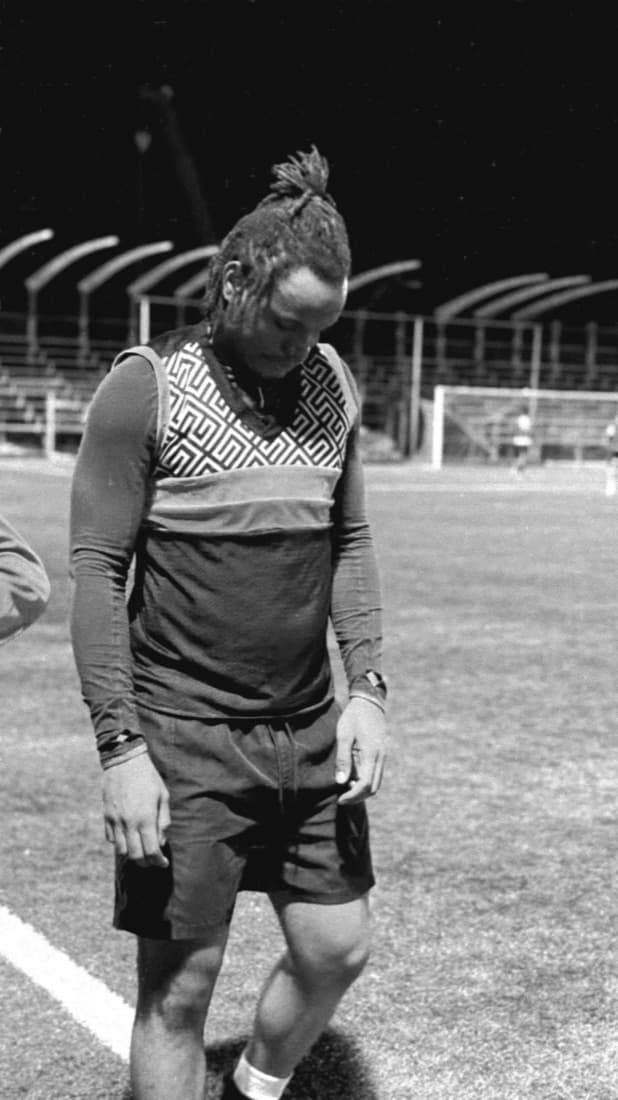 Black-and-white frame walking off the pitch, head down.