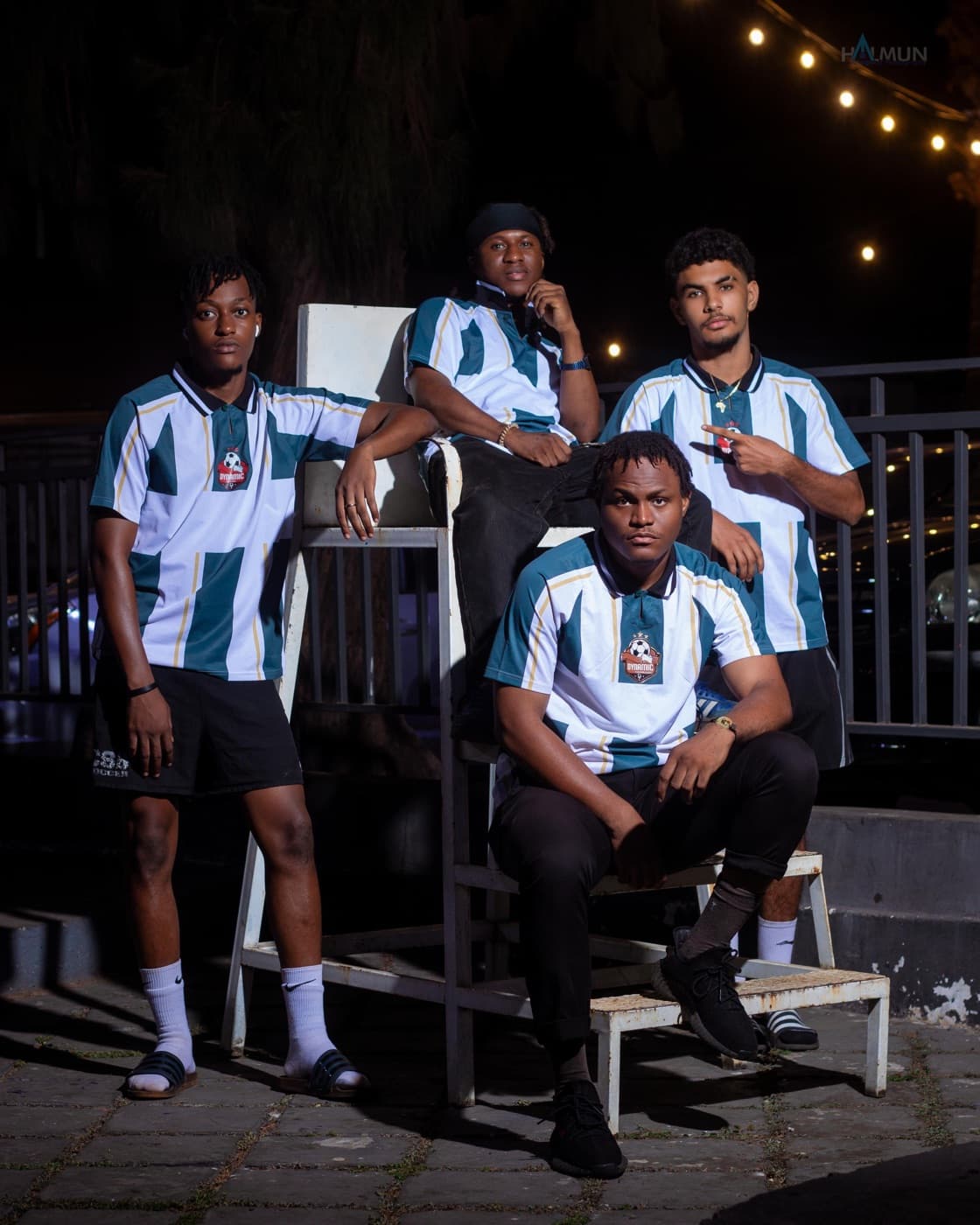 Four teammates in club kits posed around a white chair at night.