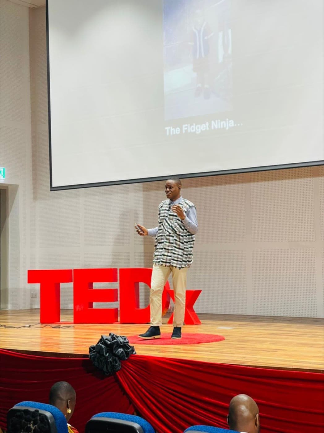 On the TEDx stage, mid-talk, the letters behind.