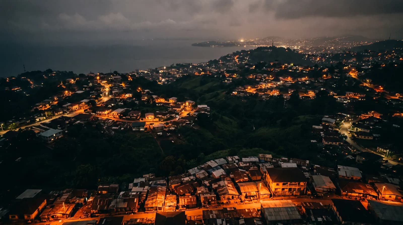 A Freetown hillside at night, a cluster of rooftops lit against the dark