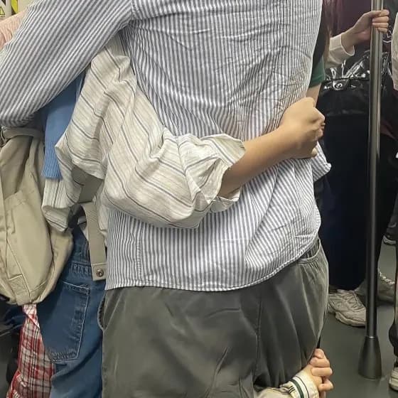 A photograph on a crowded train, one person holding another steady